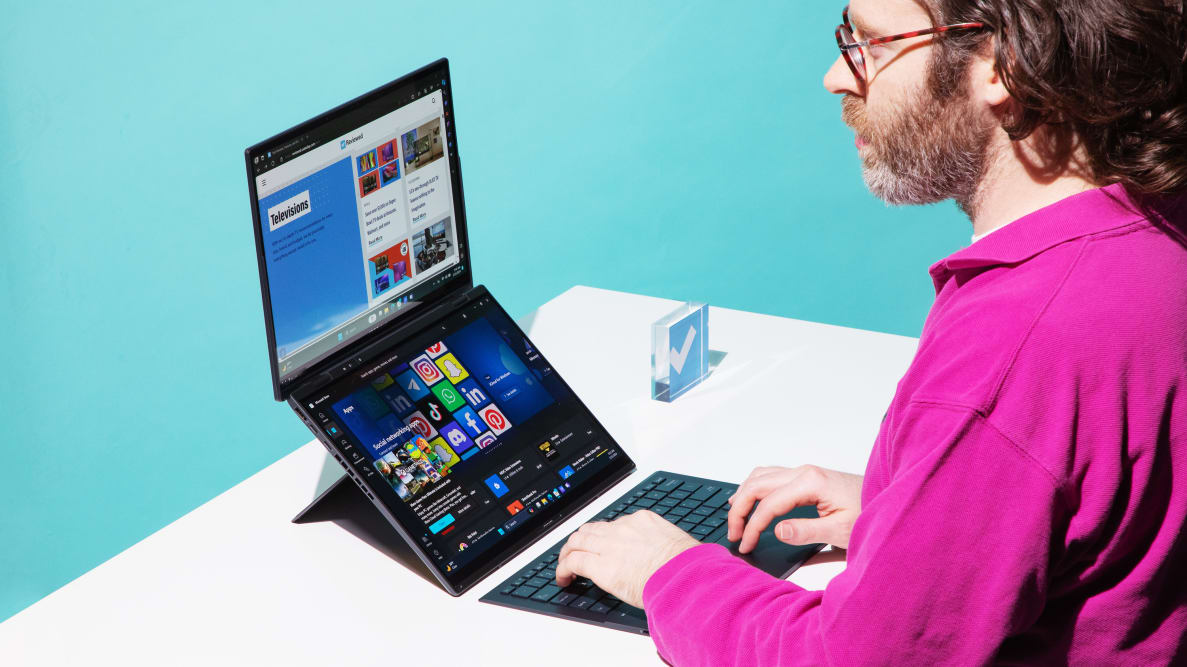 Person typing on the Asus Zenbook Duo laptop on top of a white desk.