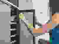 A woman pulls a bottle of wine out of a wine refrigerator.
