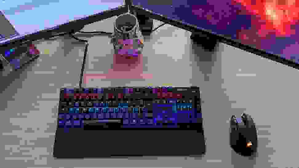 A steelseries Apex pro, one of the best gaming keyboards on the market, on a desk between two monitors tilted inward