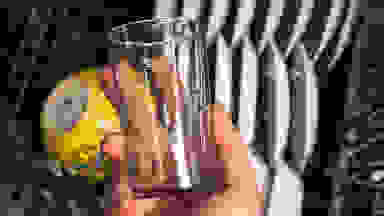 A hand holds a glass that's mostly clean, but has green flecks of redeposit marring its sheen.