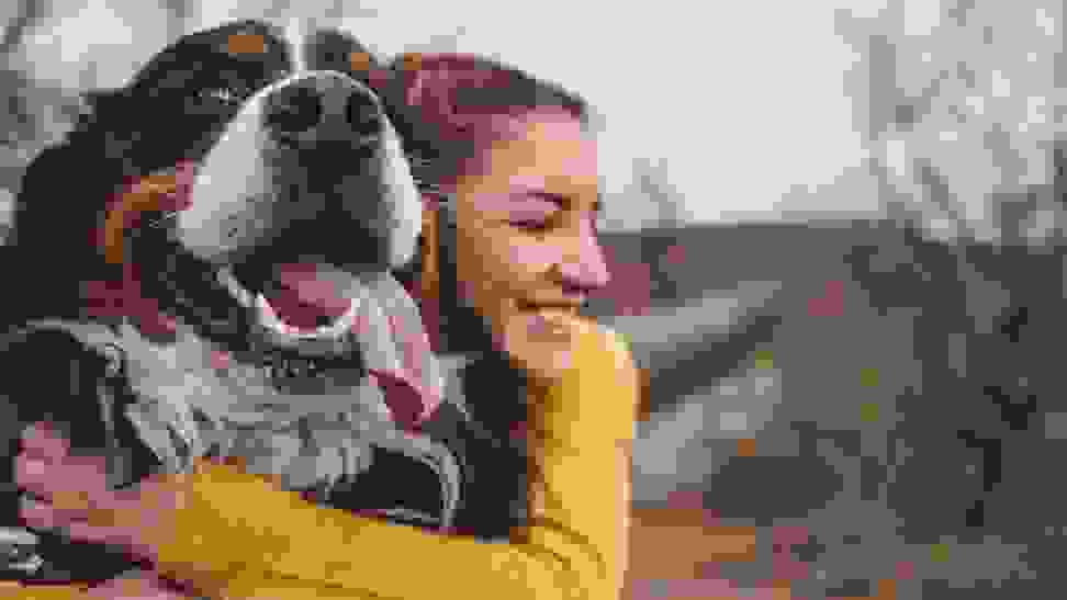 A person hugging a dog outside