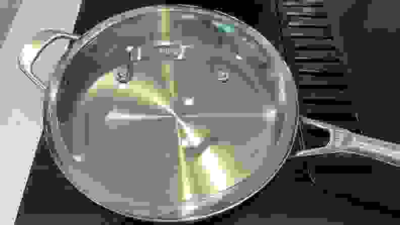 A stainless steel pan and lid on a black stove top.