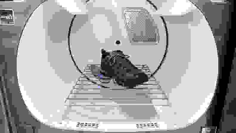 A close-up of the Maytag MED8230HC dryer's drum with the shoe rack installed. A single sneaker lays suspended on the rack, which straddles the moving parts of the drum, allowing to shoe to sit still without tumbling.