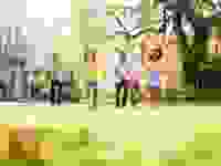 Five children run towards an Easter egg, baskets in hand and bunny ears on.