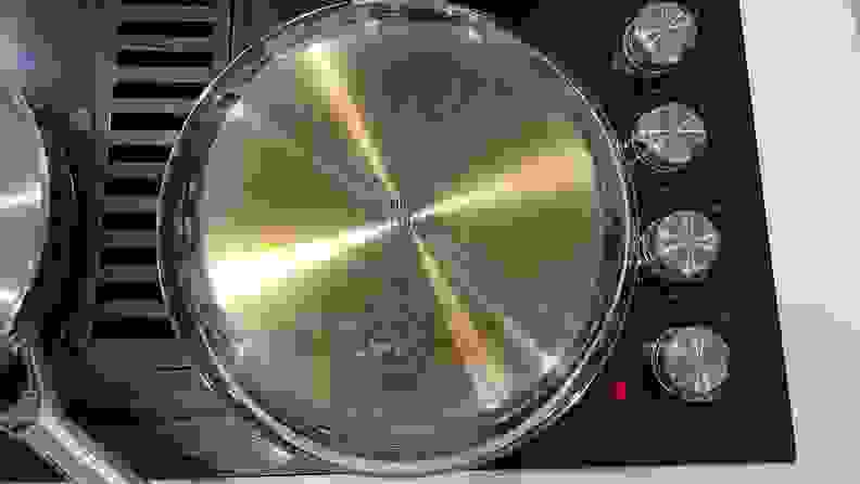 The bottom of a stainless-steel pan that's on a black stovetop.
