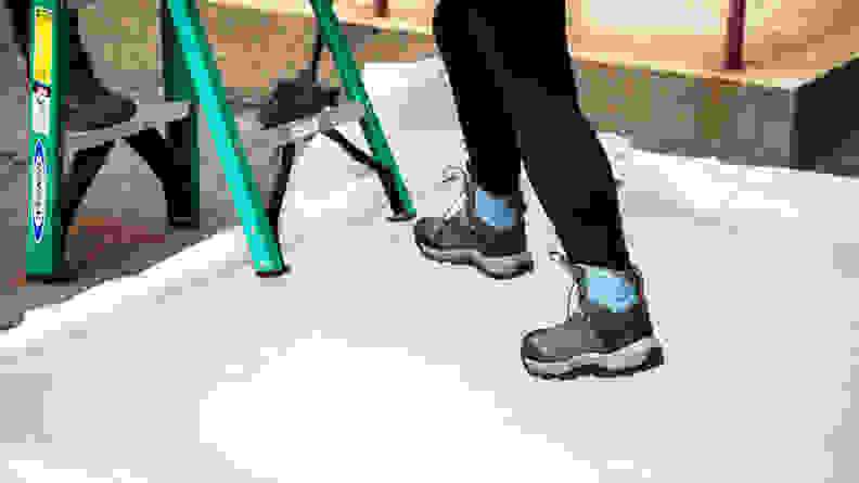 A woman is testing the traction of a pair of winter boots on a small outdoor ice rink.