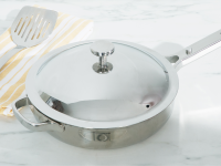 Titanium Always Pan Pro pan with lid attached next to spatula on top of a folded dishcloth.