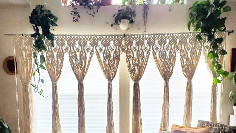 Cream colored macrame window curtain on window in bright bedroom.