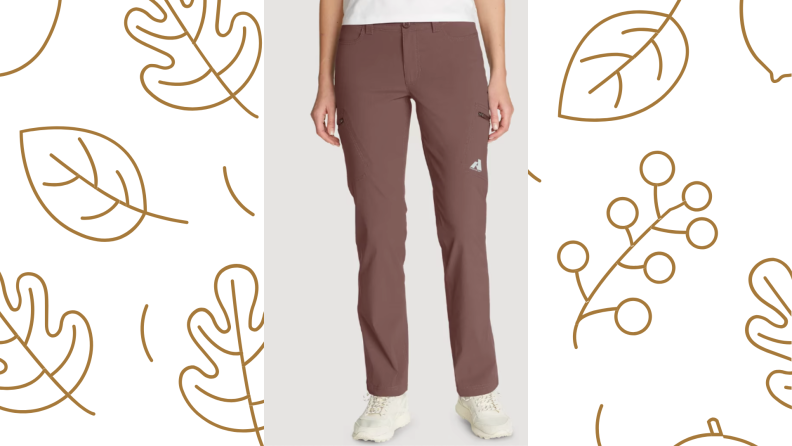 A person stands in a pair of pants from the waist down, over a leaf-printed background