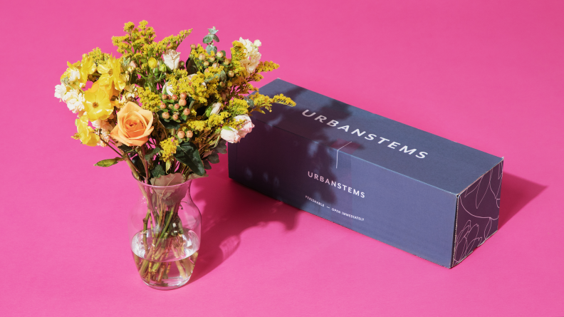 A vase of flowers next to the box they were shipped in.